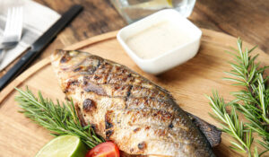 pesce arrostito con accanto ciotola di salsa bianca